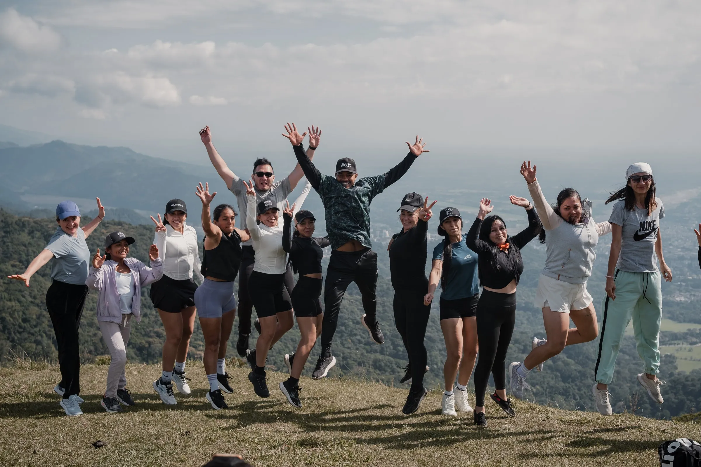 Grupo de senderistas saltando en la cima con la luz de la mañana