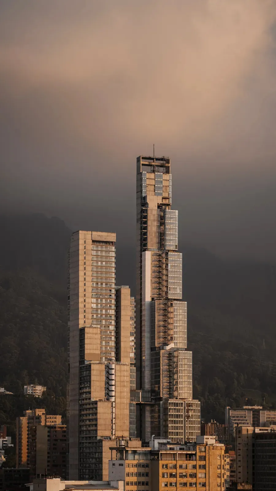 Torre escalonada sobre Bogotá al atardecer, con los cerros al fondo
